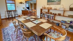 Comedor con mesa de madera, sillas, alfombra y estantería con cestas.