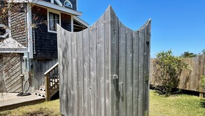 A wooden fence with a pointed top, a wooden deck, and a house in the background. - Mosby's Manor:  Eclectic design, unique interior, distant sound views. (Ocracoke)