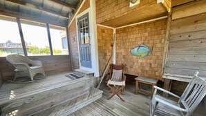 A wooden deck with a rocking chair, a folding chair, and a small table. - Mosby's Manor:  Eclectic design, unique interior, distant sound views. (Ocracoke)