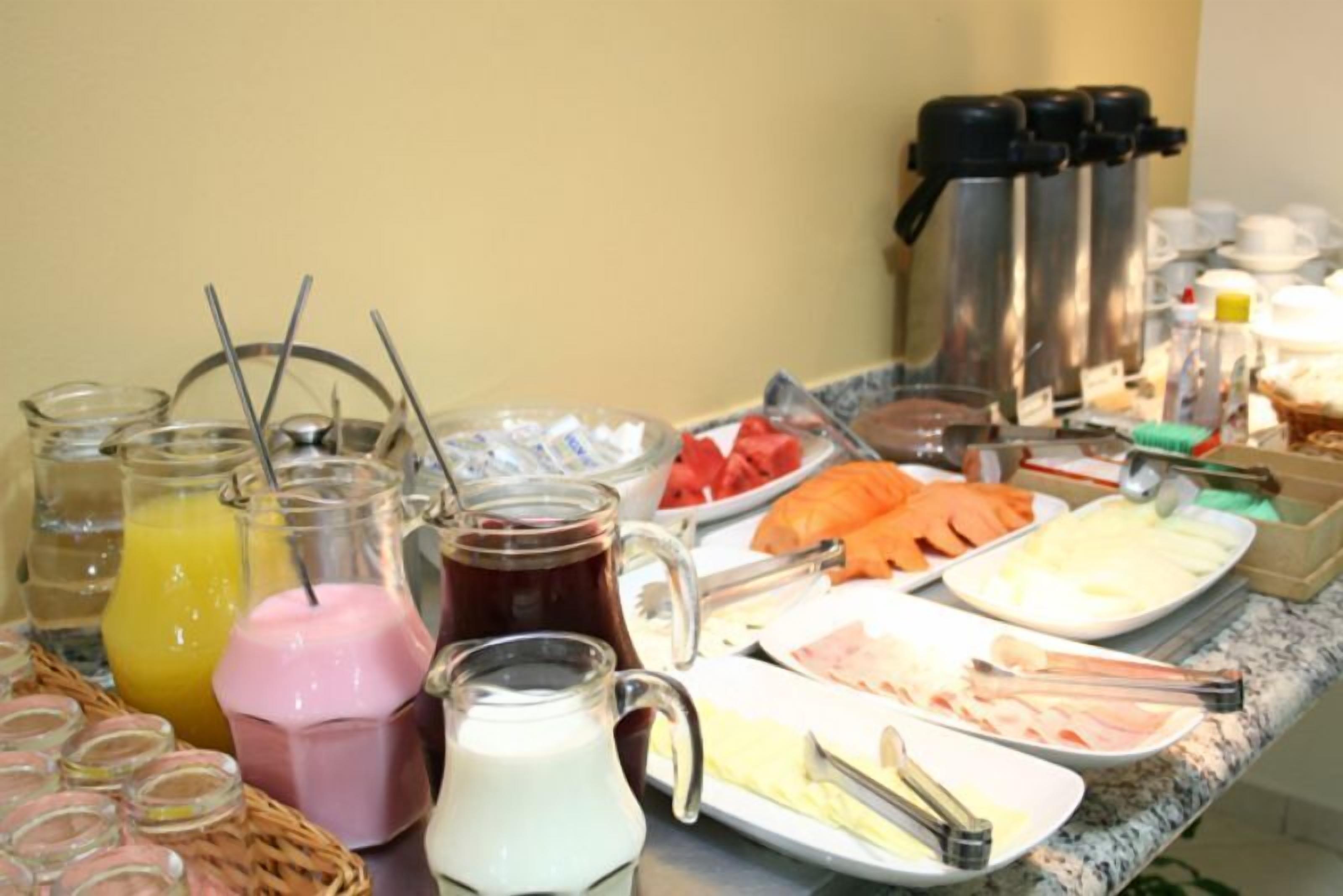 A buffet with various food items and beverages, including fruits, cheeses, and a coffee station.