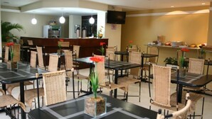 A hotel dining area with multiple tables and chairs, a reception desk, and a television on the wall. - Residence Plaza Flat (Ribeirão Preto)