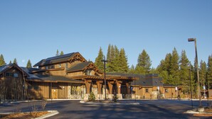 A large wooden lodge with multiple buildings, a covered entrance, and a parking area.