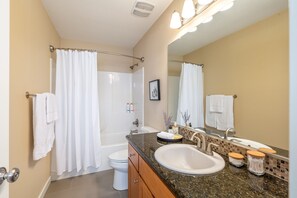 Een bad/douchecombinatie, een haardroger, handdoeken, zeep