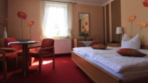 A hotel room with a bed, a desk, a chair, and a window with curtains. - Gasthaus & Pension Koch (Cursdorf)