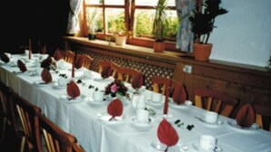 A long dining table set with white tablecloths, red leaf centerpieces, and wooden chairs. - Gasthaus & Pension Koch (Cursdorf)