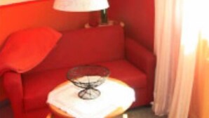 A room with a red sofa, a small table, and a lamp. - Gasthaus & Pension Koch (Cursdorf)