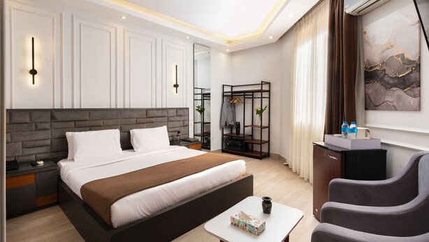 Une chambre d’hôtel moderne dotée d’un grand lit, de tables de chevet, d’un bureau et d’un coin salon.