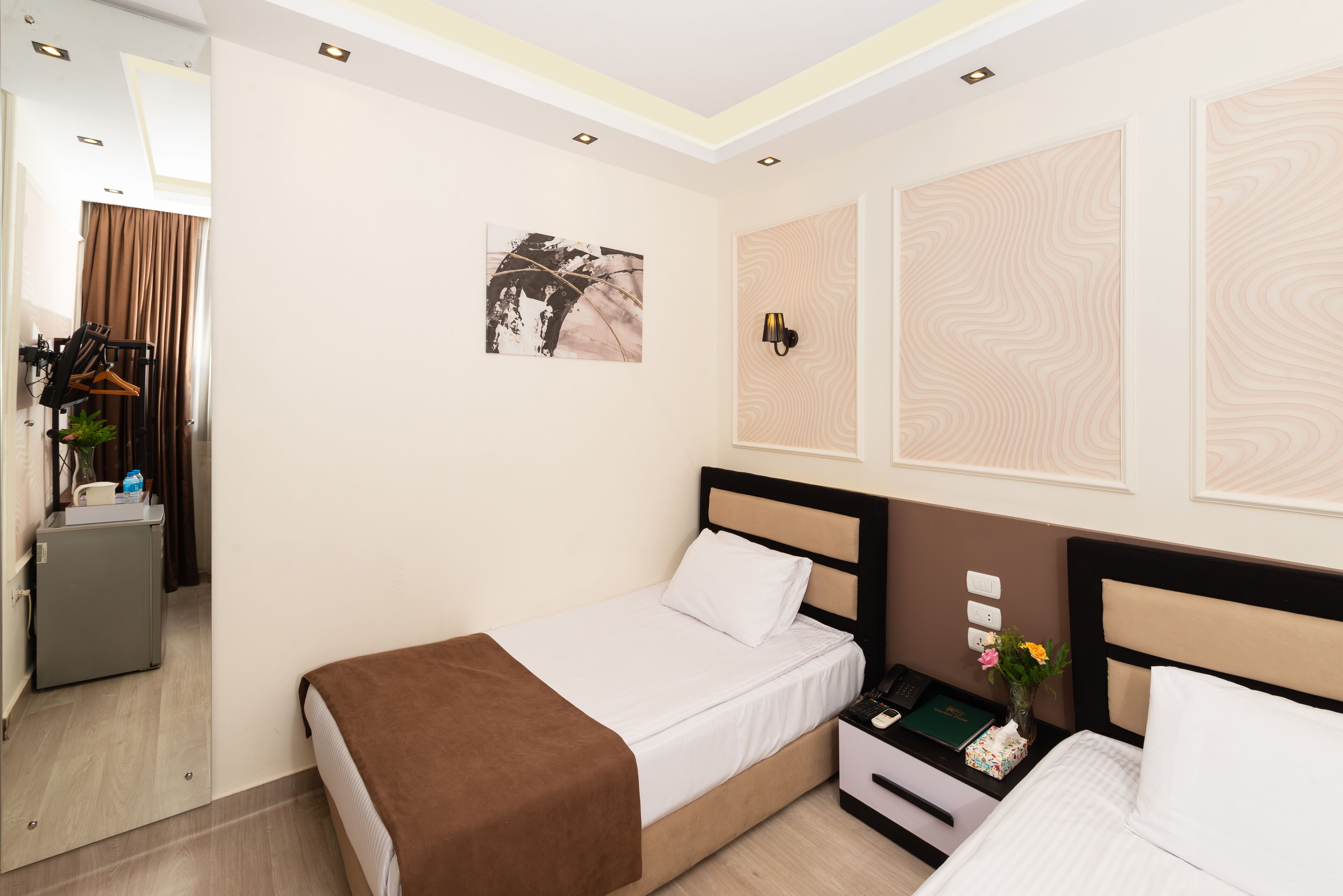 A hotel room with a bed, bedside table, and a wall-mounted lamp.