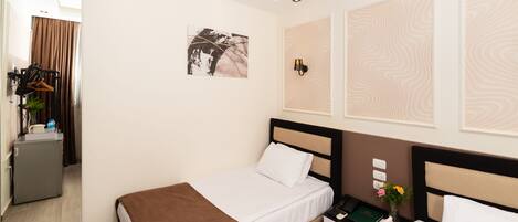 A hotel room with a bed, bedside table, and a wall-mounted lamp.