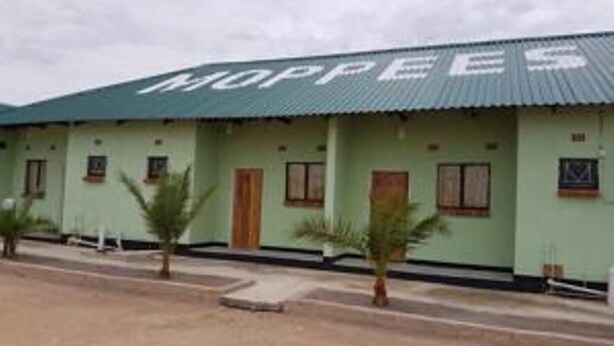 A building with a green roof and multiple windows, labeled "MOPPEE". - Mopees Lodge (Choma)