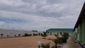 A building with a green roof and a paved area with small trees. - Mopees Lodge (Choma)