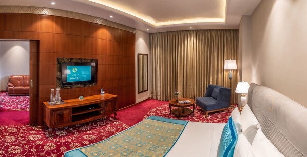 A hotel room with a TV, a sofa, a chair, a bed, and a small table. - The Abduz Leh (Leh)