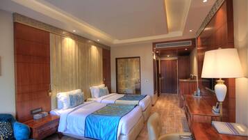 Une chambre d’hôtel avec deux lits, un bureau, une chaise, un canapé et une salle de bain.