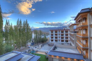 A hotel with multiple floors, outdoor seating areas, and a view of mountains in the background.