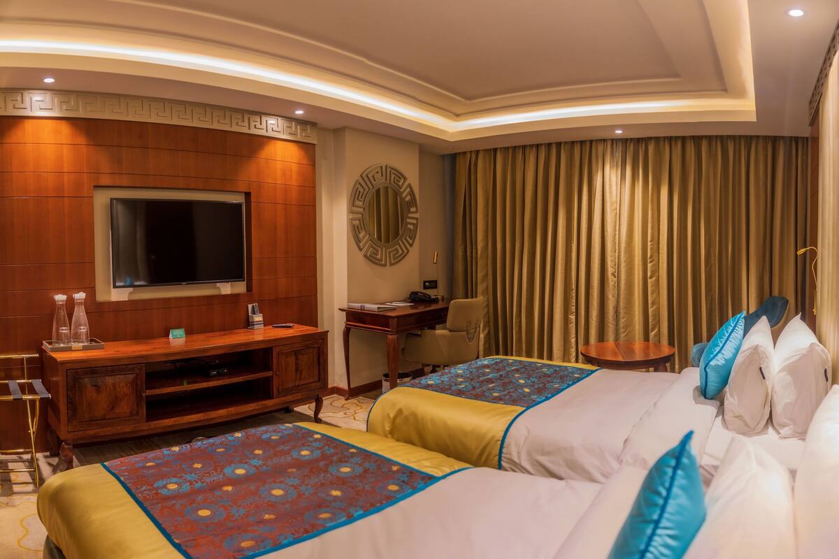 Ein Hotelzimmer mit einem großen Bett, einem Fernseher, einem Schreibtisch und einem Sessel.