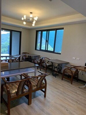 A spacious dining area with multiple tables and chairs, large windows offering a view of the outdoors, and a modern chandelier. - Kinshui Villa (Shoufeng)