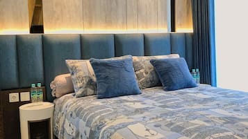Relax in a stylish room with a large bed, grey headboard, and blue accent wall, featuring a bedside table and lamp.