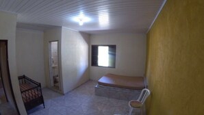 Une pièce comprenant un lit, une chaise, une petite table et une fenêtre.