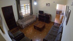 Un salon comprenant un canapé, une table basse, un meuble pour la télévision et un ventilateur de plafond.