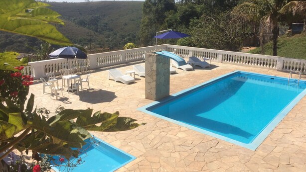 Un espace piscine comprenant deux piscines, des chaises longues et une vue sur le paysage environnant.