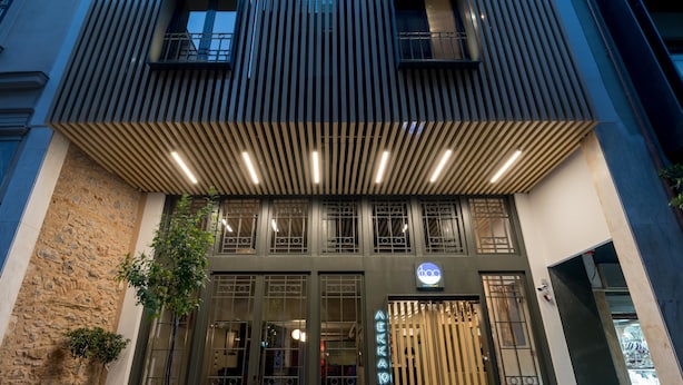 A modern building with a prominent entrance, large windows, and a sign indicating it is a hotel. - Fos DownTown Suites (Athens)