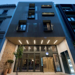 A modern building with a prominent entrance, large windows, and a sign indicating it is a hotel. - Fos DownTown Suites (Athens)