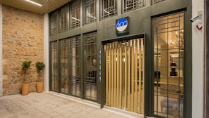 A hotel entrance with a stone facade, metal gates, and a sign indicating it is a hotel. - Fos DownTown Suites (Athens)