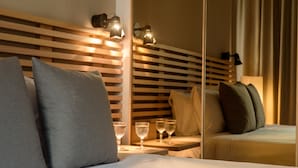 A hotel room with a bed, pillows, bedside tables, and wall-mounted lights. - Fos DownTown Suites (Athens)
