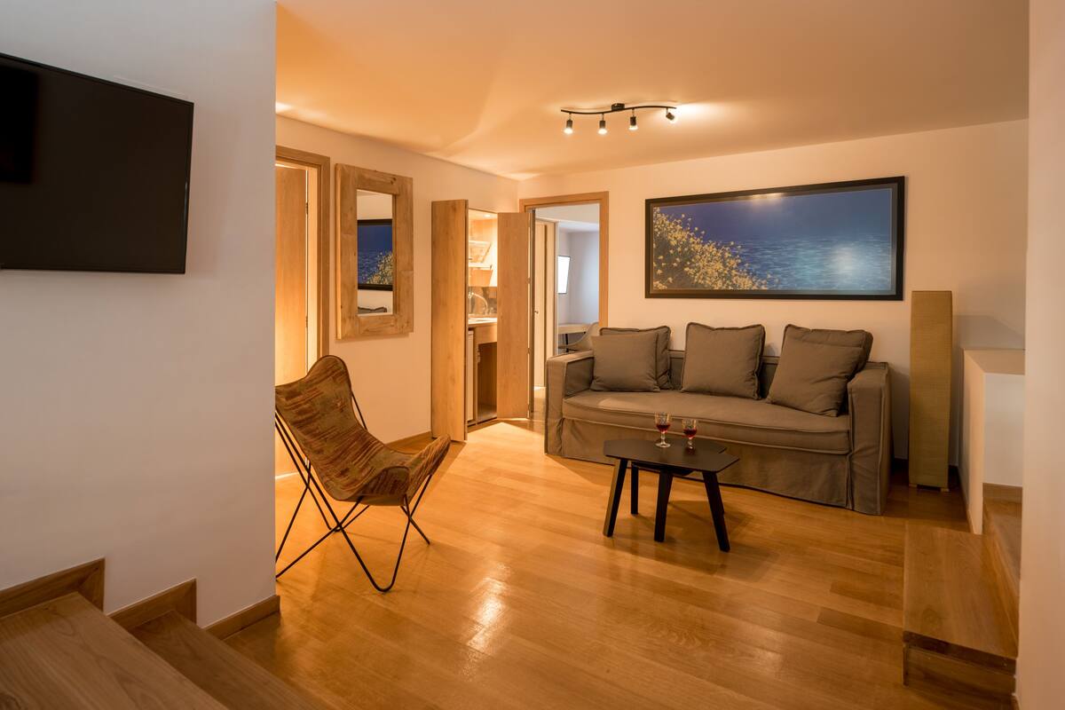A modern living room with a sofa, a coffee table, and a TV mounted on the wall.
