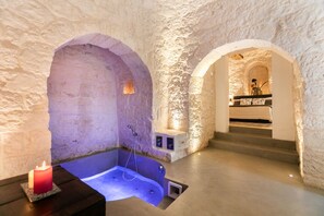 A spa area with a hot tub, stone walls, and a staircase leading to an upper level. - Dimora Ritunno (Locorotondo)