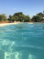 Una piscina cristalina con ondas visibles y reflejos de árboles al fondo.