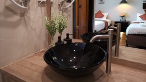 A hotel bathroom with a black bowl sink, a mirror, and two hair dryers mounted on the wall. - Fang Chiang Mai (Chiang Mai)