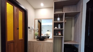 A modern bathroom with a wooden vanity, a black sink, and a mirror above it. There is a shelf with toiletries and a small black cabinet. - Fang Chiang Mai (Chiang Mai)