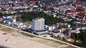 An aerial view of a coastal town with a prominent hotel, beach, and residential buildings.