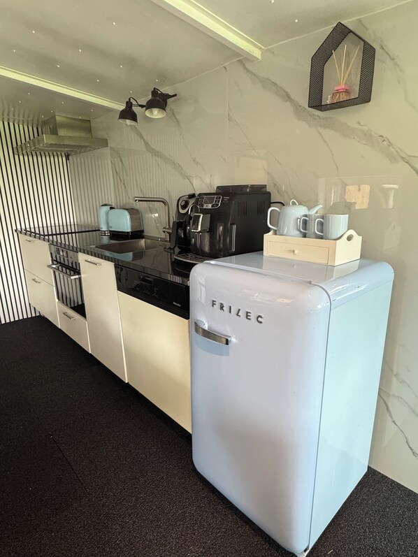 Una cocina moderna con un refrigerador blanco Frizec, una cafetera y un juego de té sobre la encimera.