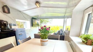 Una cocina compacta con cafetera, un refrigerador azul y una ventana con vista a zonas verdes.