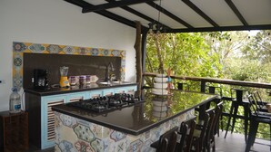 Una cocina con salpicadero de azulejos, estufa a gas y lavamanos.