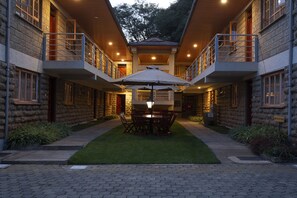 A stone building with a central courtyard, a dining table with chairs, and a reception desk. - The Cycads Suites (Nairobi)