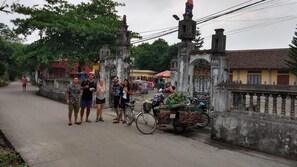 A street scene with a group of people standing near a bicycle cart loaded with vegetables. - Ninh Binh Village 1990 Homestay - Hostel (Hoa Lu)