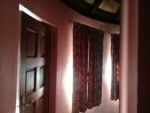 Ein Durchgang zu einem Raum, mit einer Holztür und einem Fenster mit roten Vorhängen.