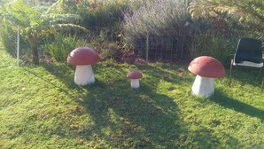 Un jardin agrémenté de trois grandes sculptures en forme de champignons et d’une chaise.
