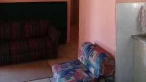 Une pièce avec un toit de chaume, un canapé, une petite table et un mur recouvert de carreaux.