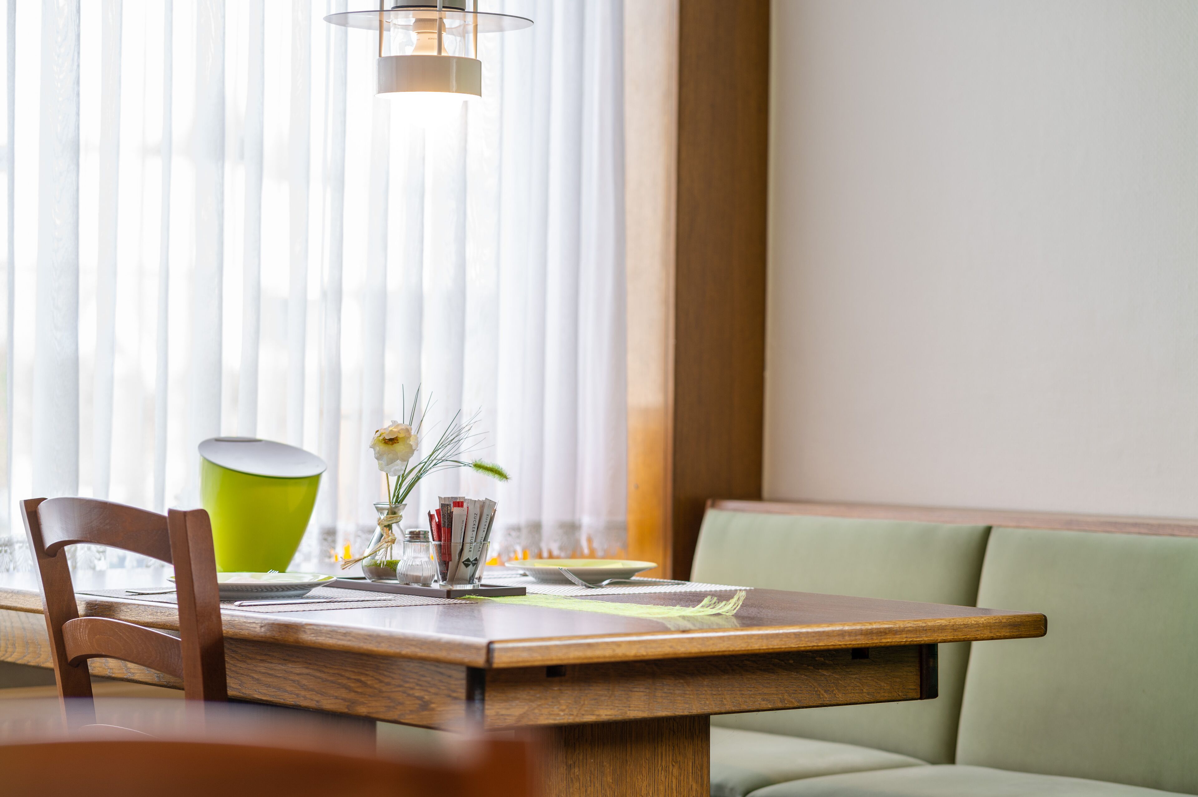 Un comedor con una mesa de madera, una silla verde y un sofá verde.