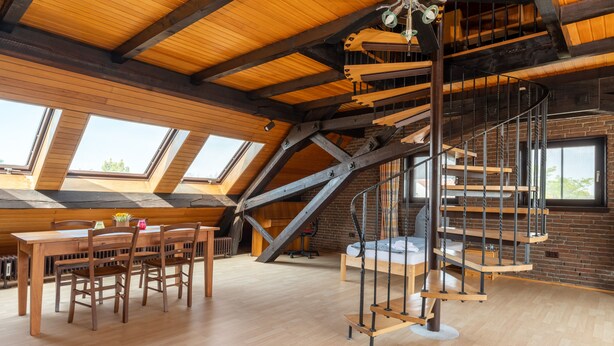 Un loft espacioso con una mesa de comedor de madera, sillas y una escalera de caracol.