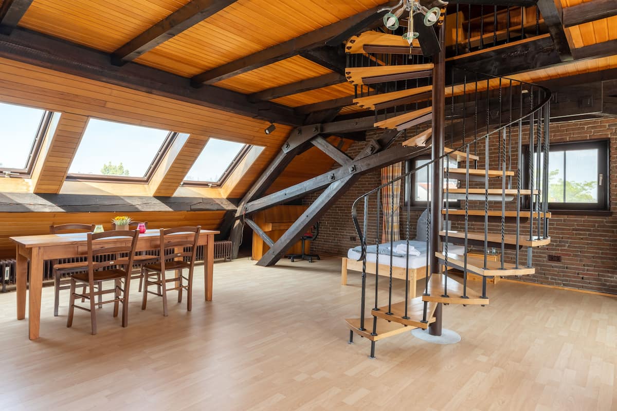 Un loft espacioso con una mesa de comedor de madera, sillas y una escalera de caracol.