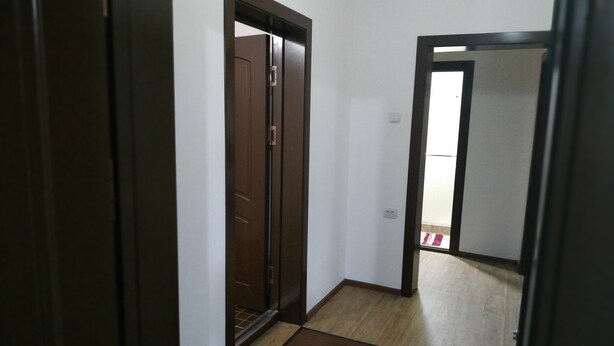 A narrow hallway with wooden flooring and a brown door at the end. - Welcome Home 20 (Tashkent)