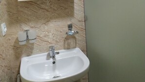 A bathroom with a white sink, a mirror, and a marble wall. - Welcome Home 20 (Tashkent)