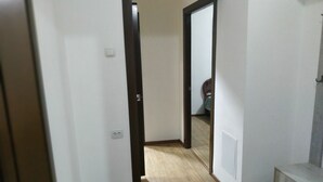 A hallway with wooden flooring, white walls, and a door leading to another room. - Welcome Home 20 (Tashkent)