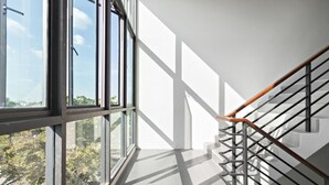 Un intérieur moderne avec un escalier, de grandes fenêtres et une vue sur la verdure environnante.