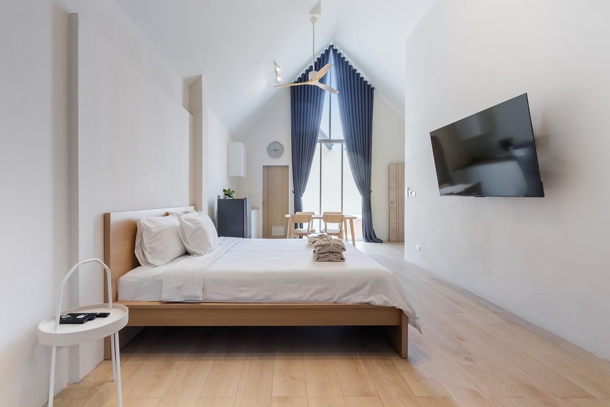 A modern bedroom with a wooden bed, a flat-screen TV, and a small table.